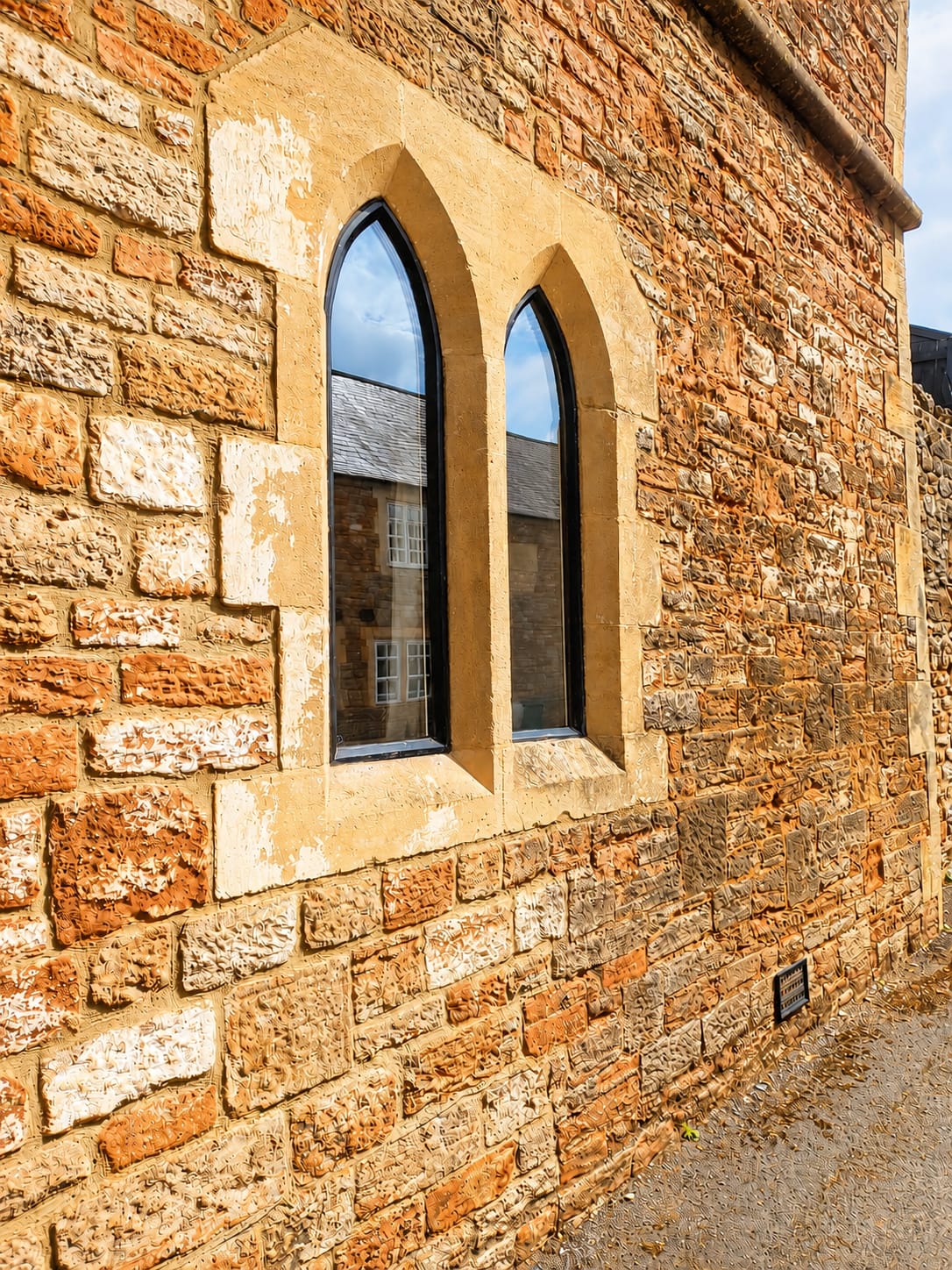 Black arched heritage windows fitted into a traditional stone wall