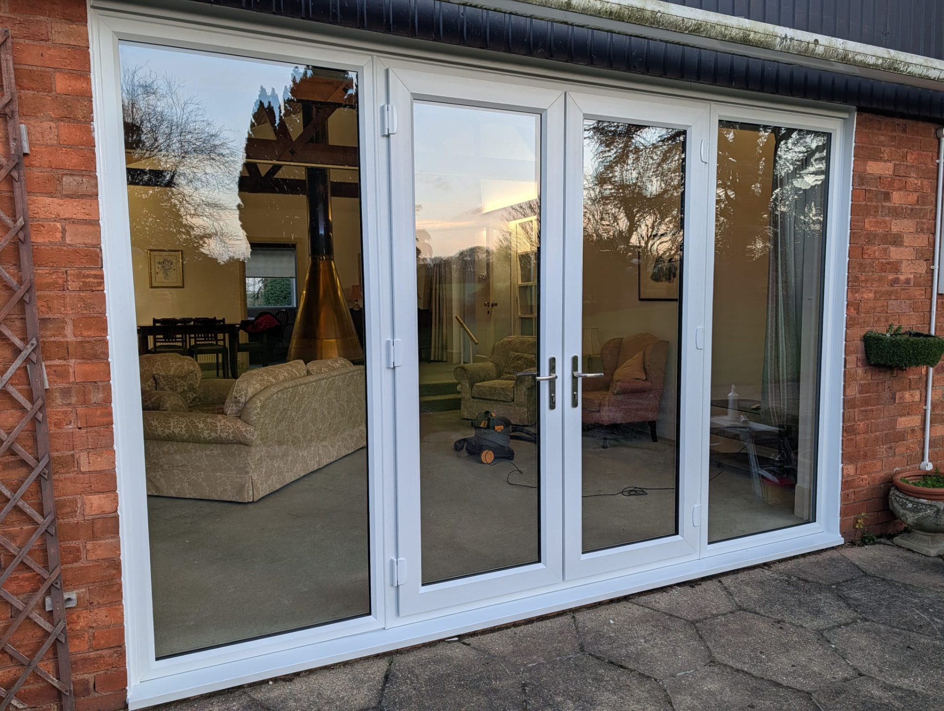 Wide white UPVC french doors with side panels on a brick property