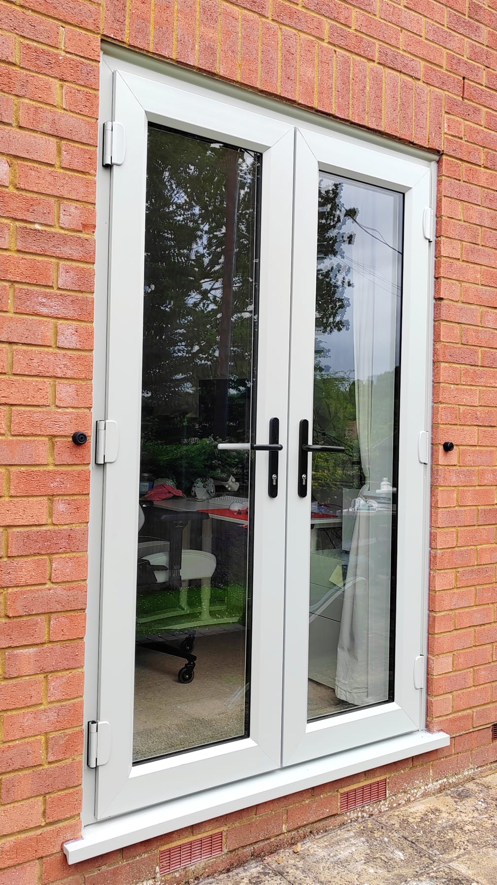 White UPVC french doors fitted to a red brick house