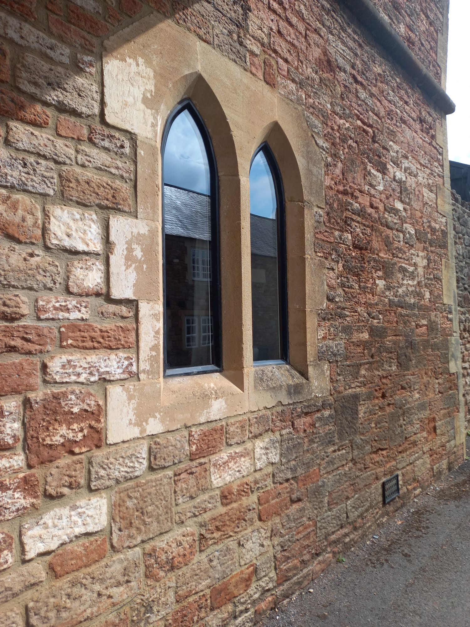 Slim-frame double glazed gothic arched windows in a stone wall